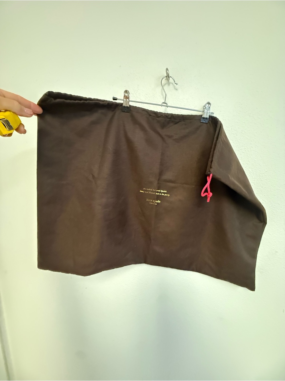 kate spade brown pouch with gold logo and yellow text
